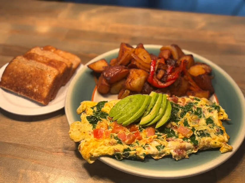 A freshly cooked veggie omelette with home fries and sourdough toast on a table near San Jose State University.